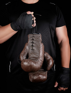 穿黑衣服的运动员拿着非常古老的棕色金拳击手套低键图片