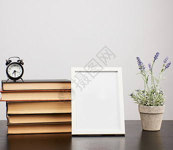 空白照片框堆叠的书籍和黑桌上种植的熏衣草锅背景图片