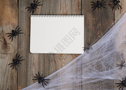 笔记本页白页蜘蛛网和黑笔记本开放以木形背景顶视图为设计图片