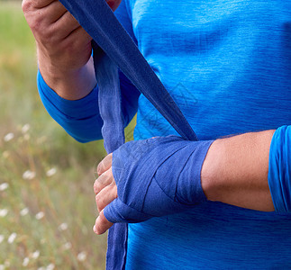 运动员在训练前户外用蓝色纺织弹绷带包住他的手高清图片