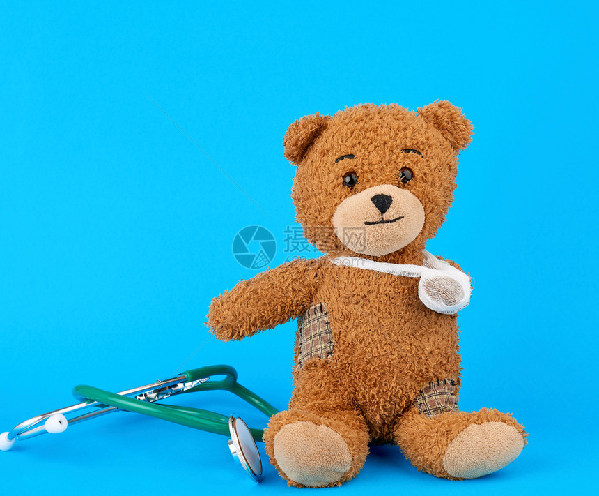棕褐色泰迪熊蓝背景上坐着绷带爪子图片