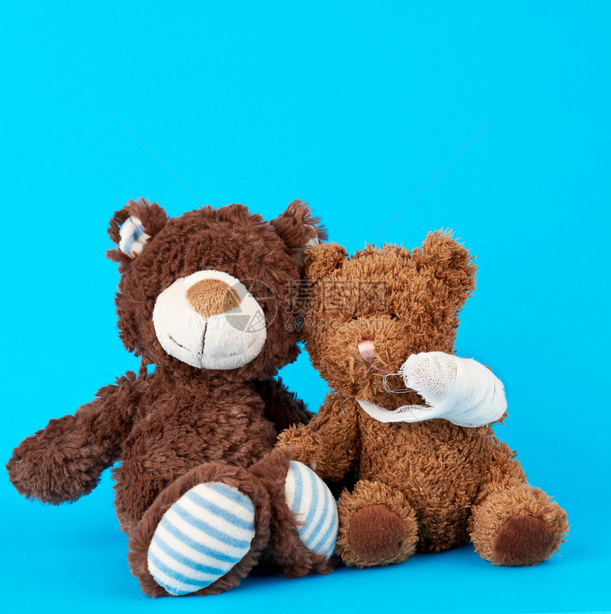 棕色泰迪熊蓝底带双声白绷爪儿科概念图片