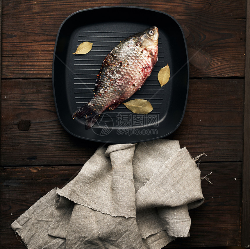 满香料的新鲜鱼躺在黑方锅里木板上的桌最面风景图片