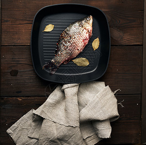 满香料的新鲜鱼躺在黑方锅里木板上的桌最面风景背景图片