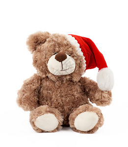 棕色帽子穿着红圣诞帽子的可爱棕色小泰迪熊坐在孤立的白色背景上度假玩具背景