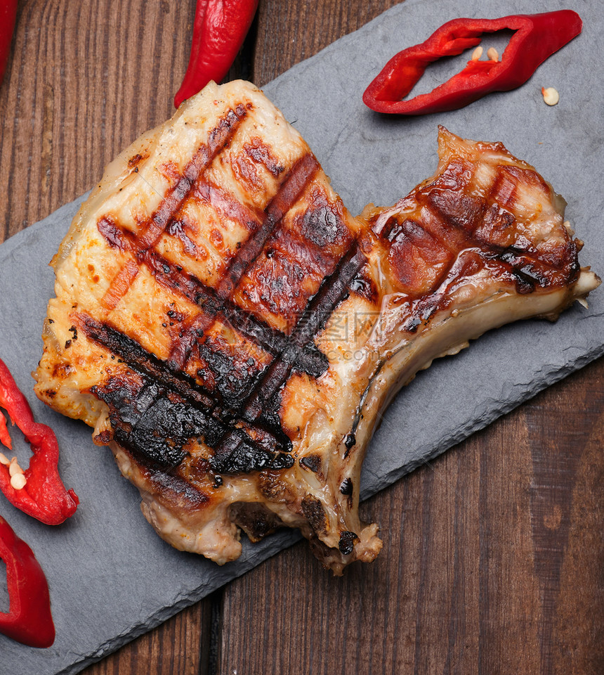 肋骨上的猪肉炸牛排躺在黑板上旁边是新鲜红辣椒图片