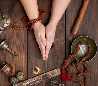 两手在青藏冥想工具替代药物顶视中的木制棕色桌子上做祈祷姿势图片