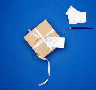 纸板礼品方箱用白色薄丝带和空卡绑在深蓝色背景顶视图趋势颜色上图片