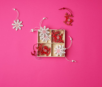 木雕刻的圣诞装饰用于在粉红背景平躺的假日树上制作圣诞装饰品图片