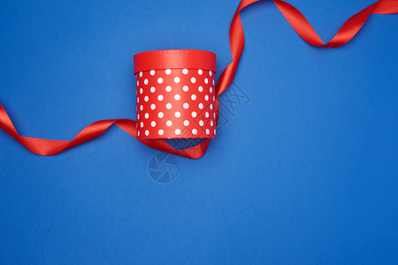 蓝色背景假日带白波尔卡点和红丝带的封闭纸板红箱背景图片