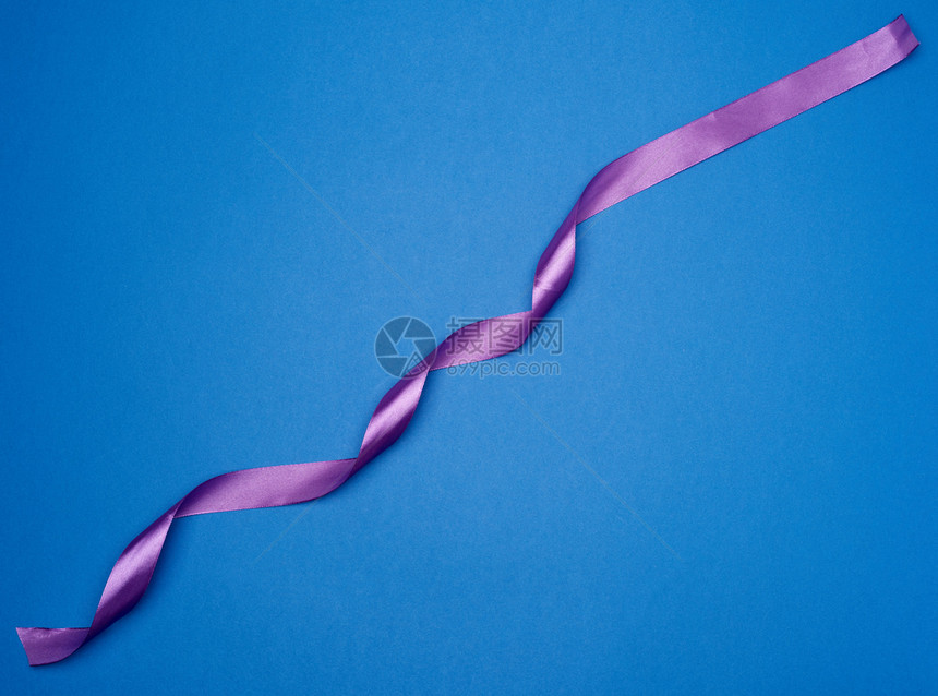紫色丝绸薄带以蓝色背景潮时颜顶视图扭曲图片