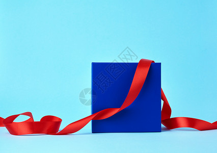 蓝纸箱用于赠品和蓝色背景的扭曲丝绸红色带背景图片