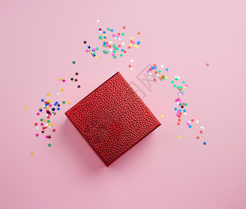粉红色背景上的正方形闪光盒和多色火花假日概念软件包设计节日概念图片