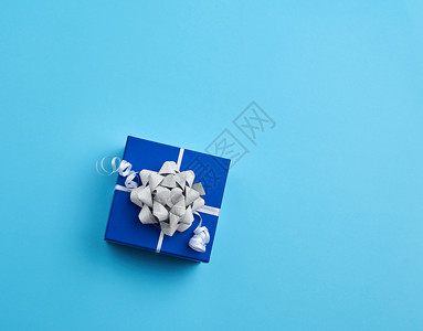 纸板礼品箱弓蓝背景的丝带顶部视图图片