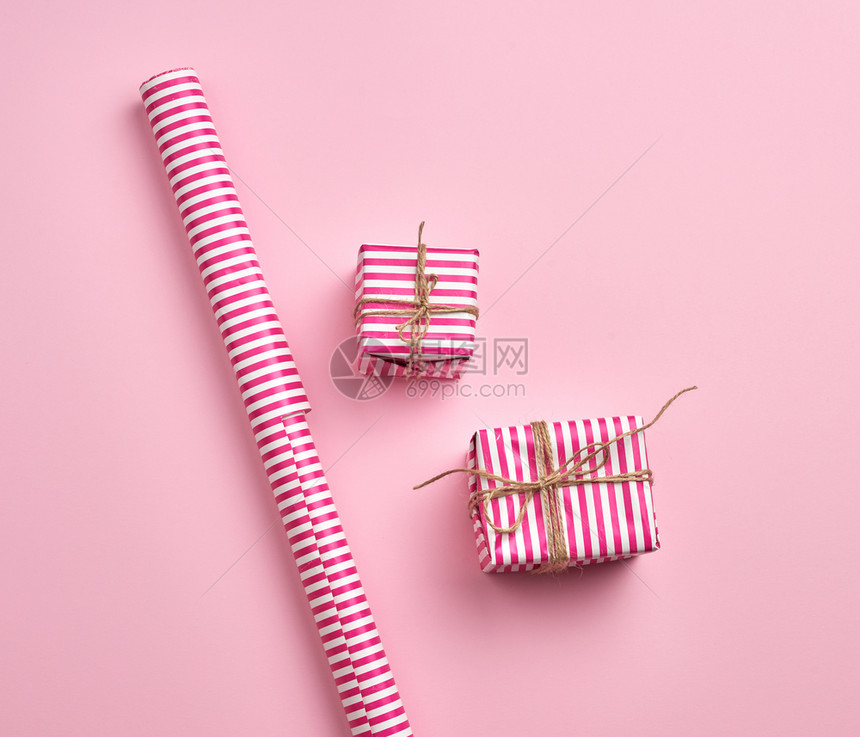 粉红背景顶视图复制空间上的粉红条纹纸和卷包着的两件礼品图片