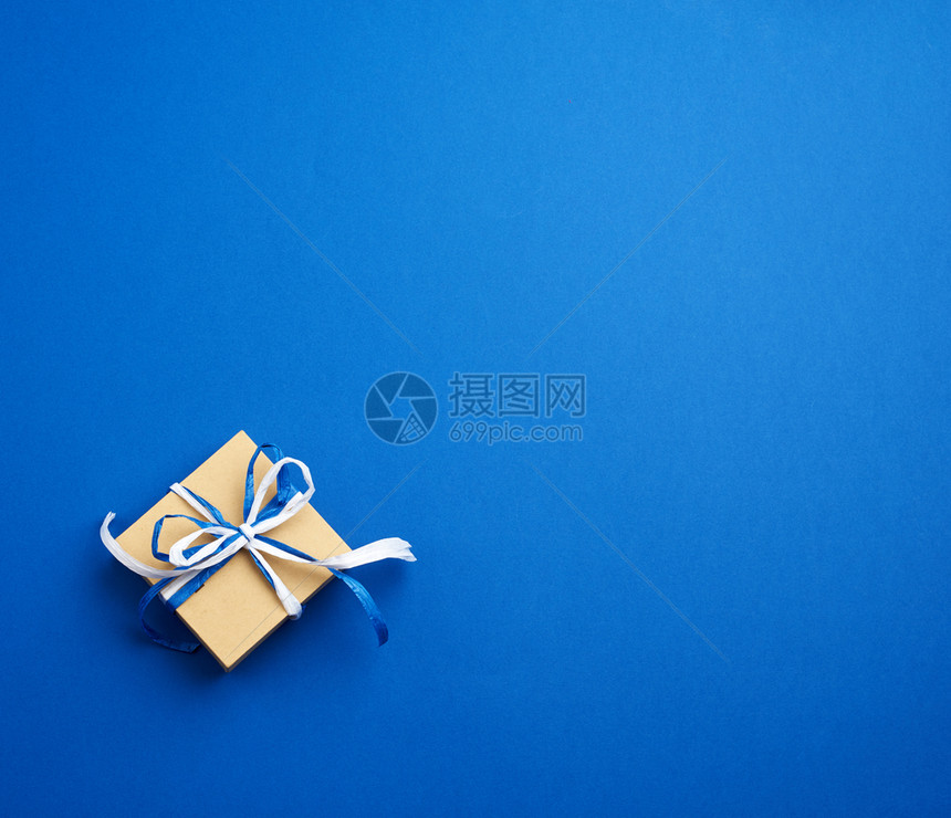 棕色纸板礼品箱蓝背景的弓顶视图图片