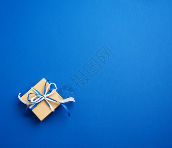 棕色纸板礼品箱蓝背景的弓顶视图图片