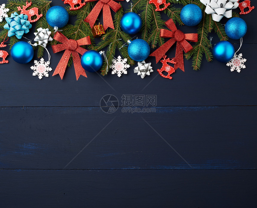 绿树枝圣诞蓝球和粉色红闪亮弓和木板上蓝背景的雕装饰图片