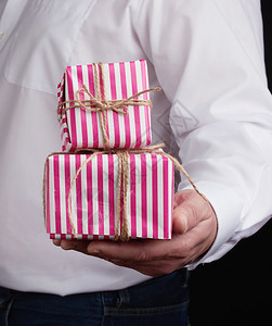 穿白衬衫的成年男子拿着粉红礼品纸箱庆祝节日周年纪念惊喜的概图片