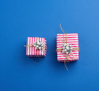 包在蓝背景顶视图假日背景的粉红条纹纸上两件礼物图片
