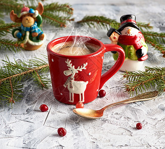 红瓷杯加黑咖啡靠近绿树枝和圣诞玩具图片