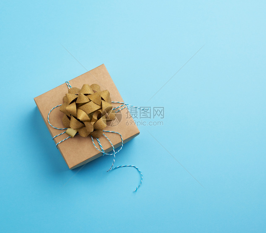 褐色方形盒带有礼品领的礼在蓝色背景顶面视图空的刻字位置上弓图片