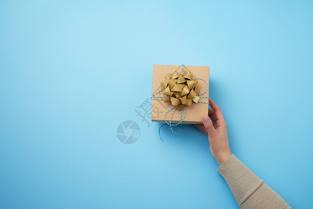 女手握着一个方形盒子在蓝色背景上鞠躬祝贺生日快乐的概念文本位置图片
