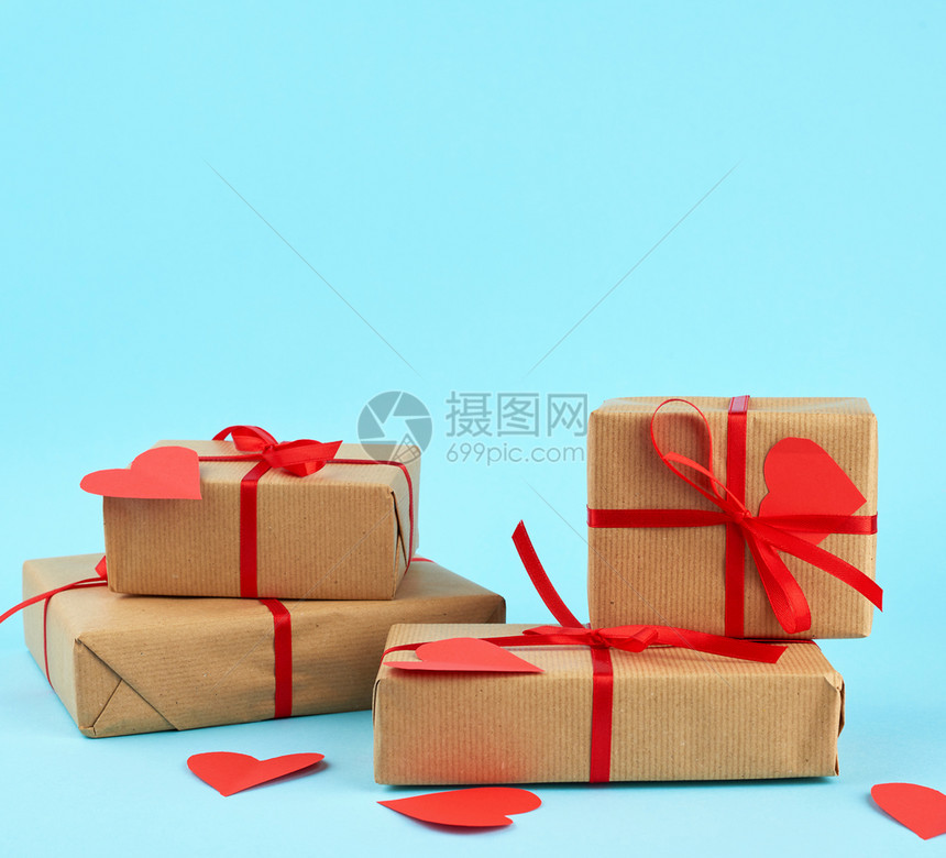 包成堆的礼物印在棕色的Kraft纸上与蓝色背景的红丝带绑在一起惊喜和情人节礼物2月14日图片