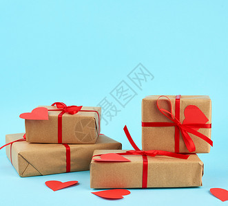 包印造纸包成堆的礼物印在棕色的Kraft纸上与蓝色背景的红丝带绑在一起惊喜和情人节礼物2月14日背景