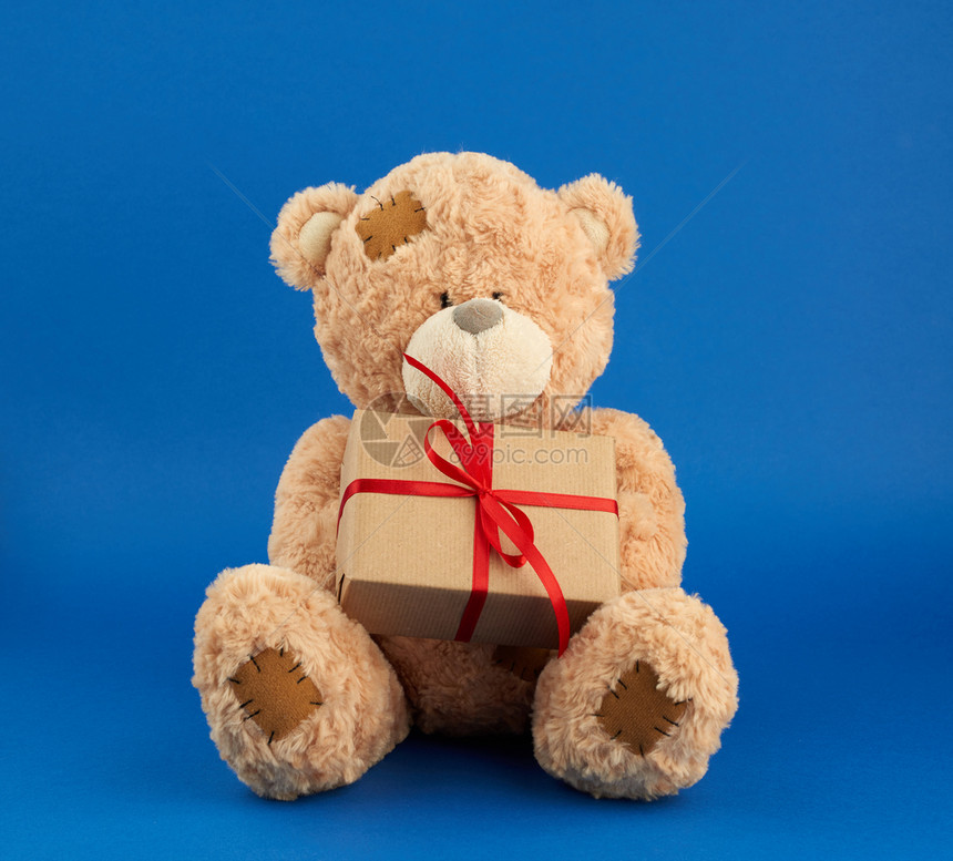 在情人节和生日时大米吉泰迪熊拿着一个包棕纸的盒子图片