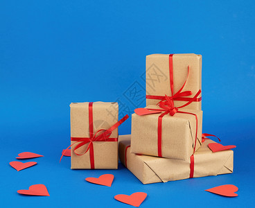 包印造纸包成堆的礼物印在棕色的Kraft纸上与蓝色背景的红丝带绑在一起惊喜和情人节礼物2月14日背景