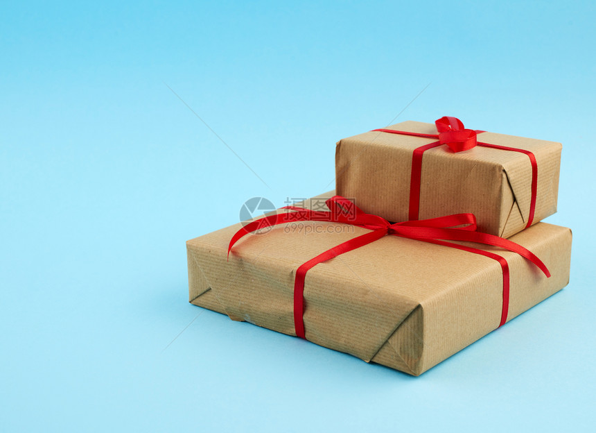 包裹在棕纸上并绑红弓蓝色背景的礼物文字位置图片
