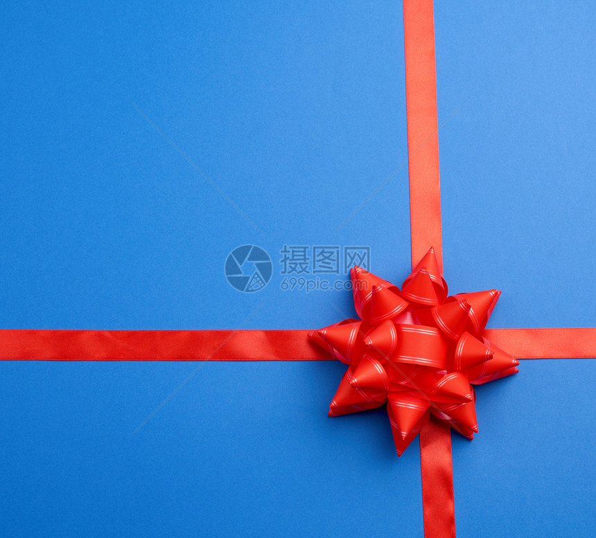 红丝带穿在弓中间的蓝背景上仿佛绑着礼物顶视线图片