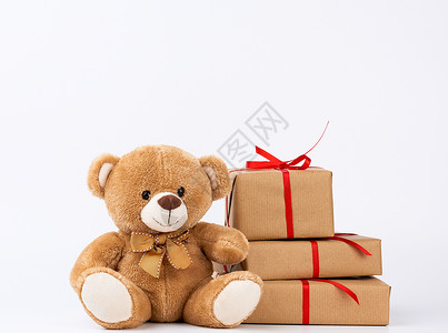 以棕色生态纸包着的盒子里装满礼物白色背景上绑着丝绸红带生日快乐和情人节背景图片