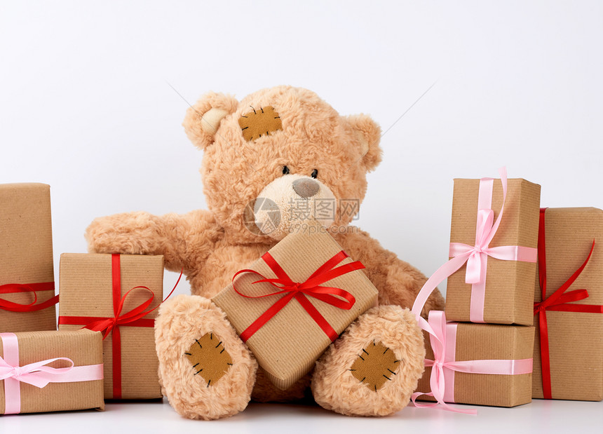 大米吉泰迪熊有补丁一堆礼物装在包着棕纸的盒子里带丝绑在白色背景上生日快乐和情人节图片