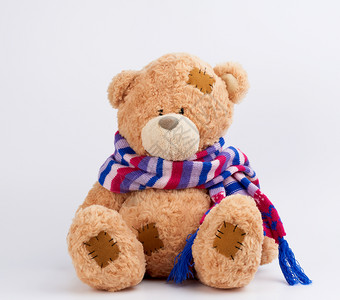 棕色可爱泰迪熊有彩色织围巾上的补丁坐在白色背景上关图片