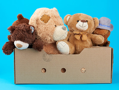 棕色纸板箱有各种泰迪熊蓝背景援助概念和志愿工作图片