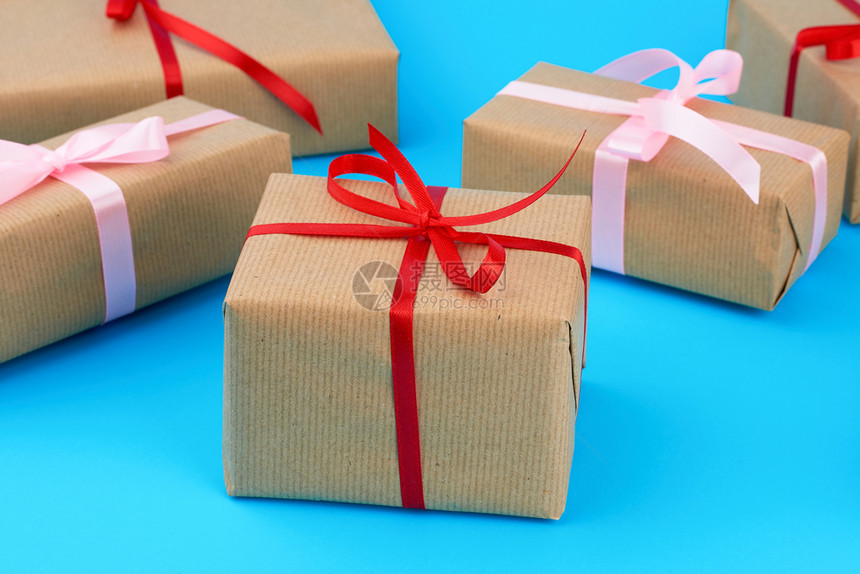 包在棕色纸上绑丝带礼物放在蓝色背景顶级视图上图片