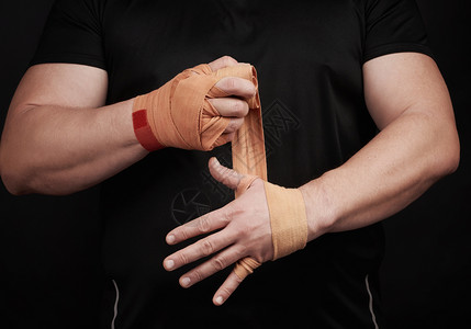 运动员身着黑色衣服在训练前用红色纺织弹橙绷带黑背景肌肉身体包着手图片
