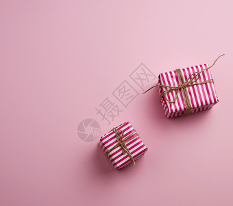 粉红背景的色条纹纸包着两件礼物顶视图复制空间图片