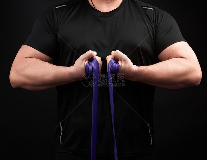 身穿黑色衣服肌肉身的运动员正在用低键蓝橡胶进行体操图片