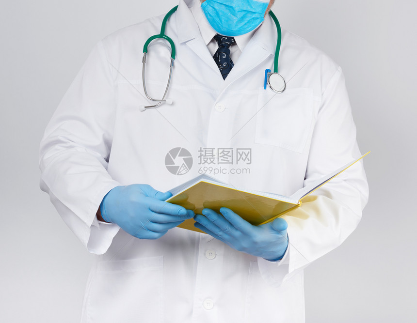 穿白色大衣的医生蓝色乳胶消毒手套在白色背景的上握着张开的黄色笔记本即探视病人时记录诊断的概念图片