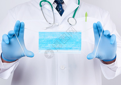 防烫手套穿白色大衣的医生蓝色乳胶消毒手套白色背面戴着纺织罩防和细菌的保护辅助剂背景