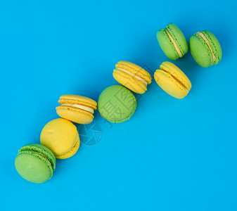 黄和绿圆杏仁面粉蛋糕加奶油蓝底霜淇淋美味的糕点顶视图图片