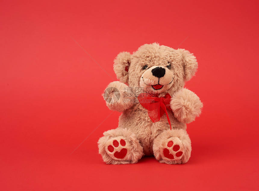 可爱的棕色小泰迪熊玩具坐在红色背景关闭复制空间图片