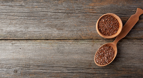 褐色棕干麻种子用棕色木制勺子用灰色木制板上的灰色木制桌子顶视角背景图片
