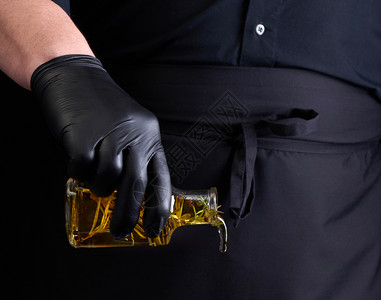 黑衣男子乳胶手套装着一个透明瓶子含橄榄油低密匙图片
