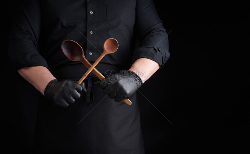 黑色乳胶手套和制服的厨师在前面交叉木制旧勺子低密钥复制空间图片