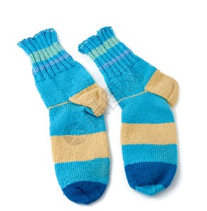 由羊毛蓝衣和白色背景隔绝的蓝衣服制成两对条纹状手工编织的暖袜子图片