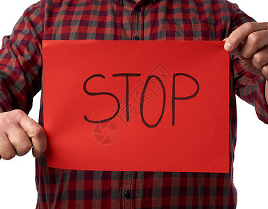 穿红格斗的成人男子穿红格式折叠衬衫的男子拿着一张红色纸上面写着句号概念停止惊慌背景图片